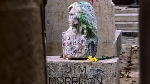 Getty Images The bust of Jim Morrison, covered with graffiti, at his grave in Paris's famous Père-Lachaise cemetery